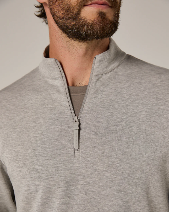 Man wearing a gray quarter zip-up sweatshirt against a neutral background