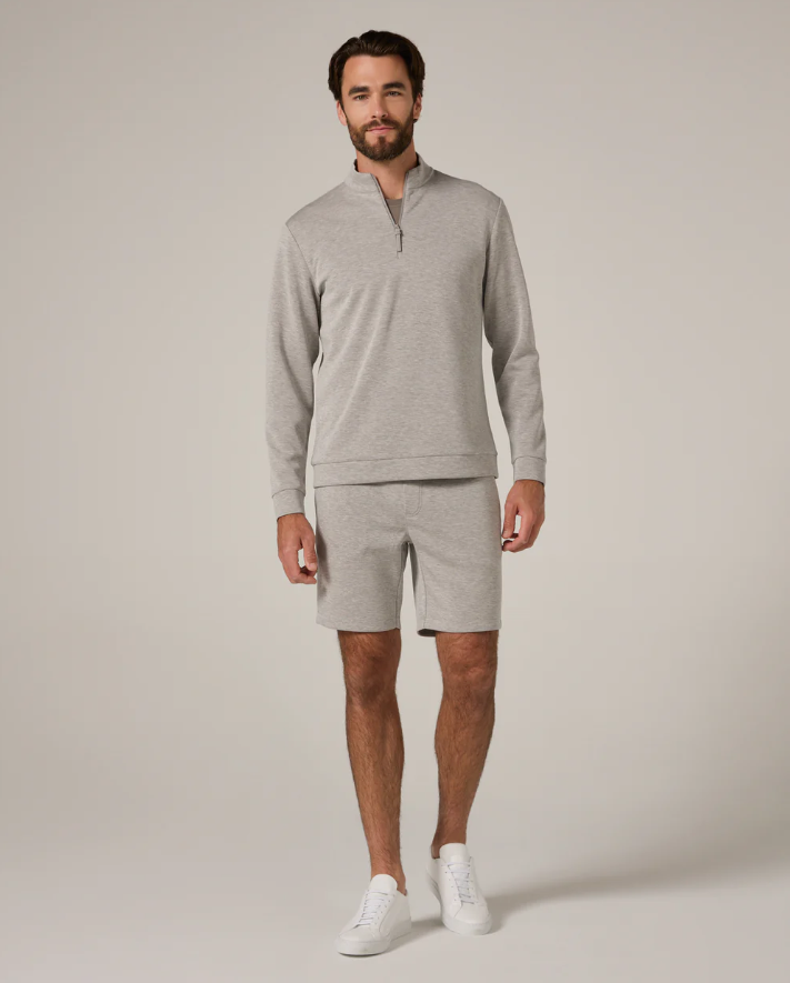Man wearing a gray long-sleeve quarter zip and shorts on a beige background