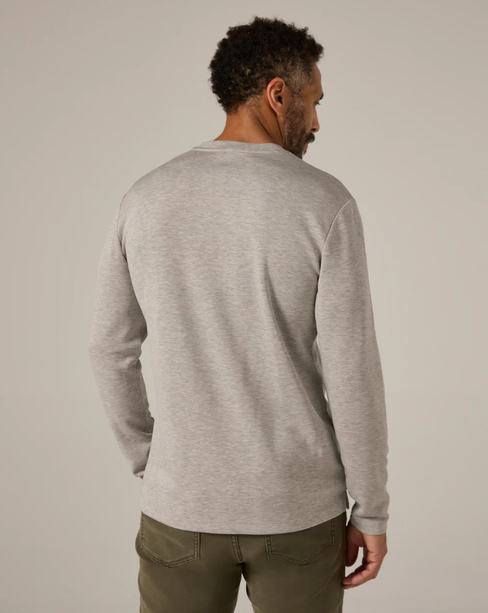 Man wearing a gray sweater and green pants against a plain background