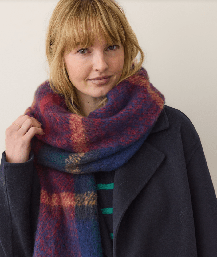 Woman wearing a colorful plaid scarf against a plain background