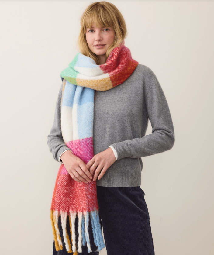 Woman wearing a colorful scarf and gray sweater on a plain background