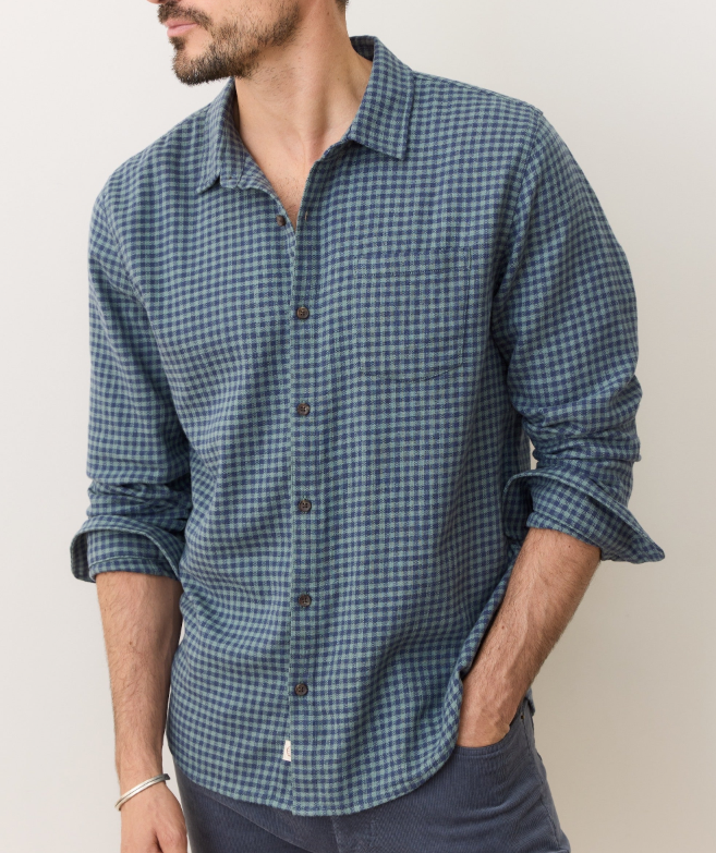 Man wearing a blue and green gingham button down shirt against a plain background