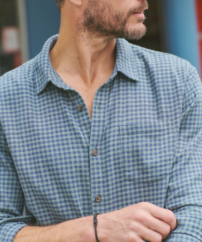 Man wearing a blue and green checkered shirt with a blurred background