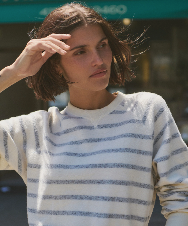 Woman wearing a white and black striped sweater with a blurred background