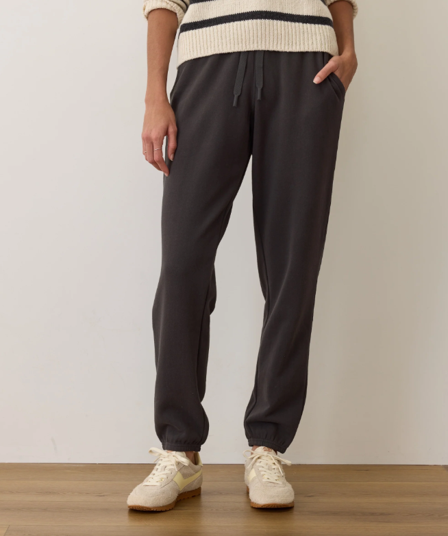 Person wearing black sweatpants and a cream sweater with a white background