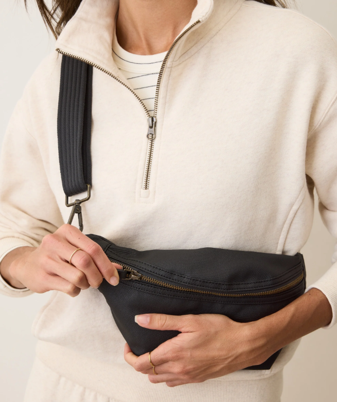 Person holding a black fanny pack with a neutral background