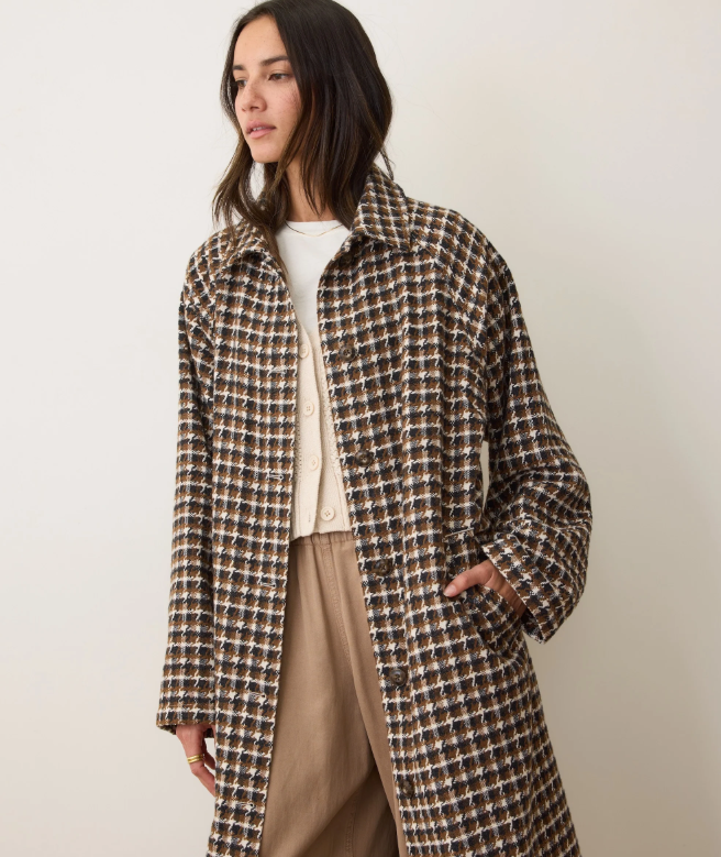 Woman wearing a brown houndstooth coat against a plain background