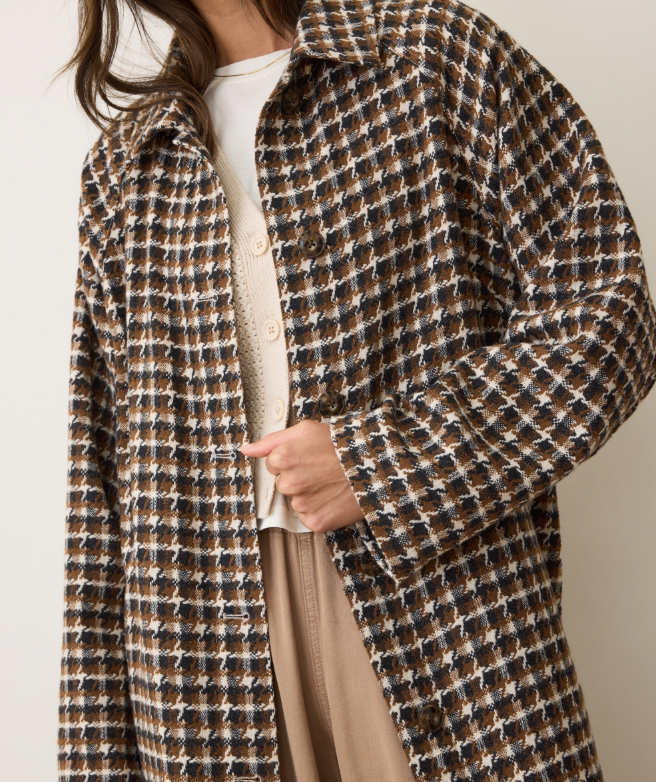 Person wearing a brown houndstooth patterned coat with a neutral background