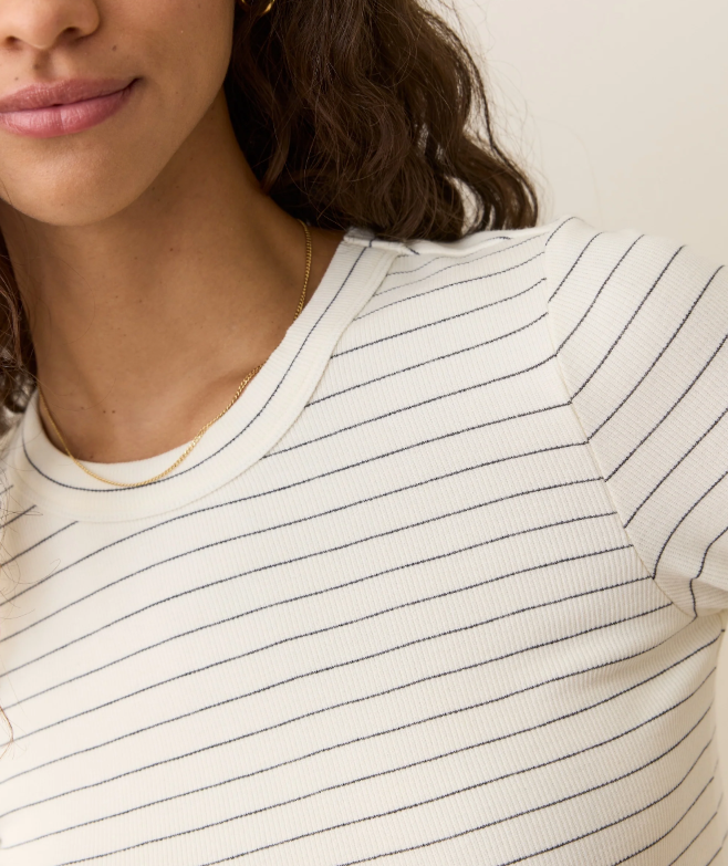 Close-up of a person wearing a white long-sleeve shirt with thin black stripes.