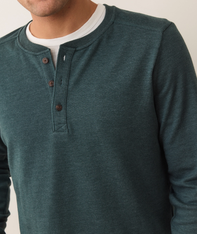 Green henley shirt worn by a person on a plain background