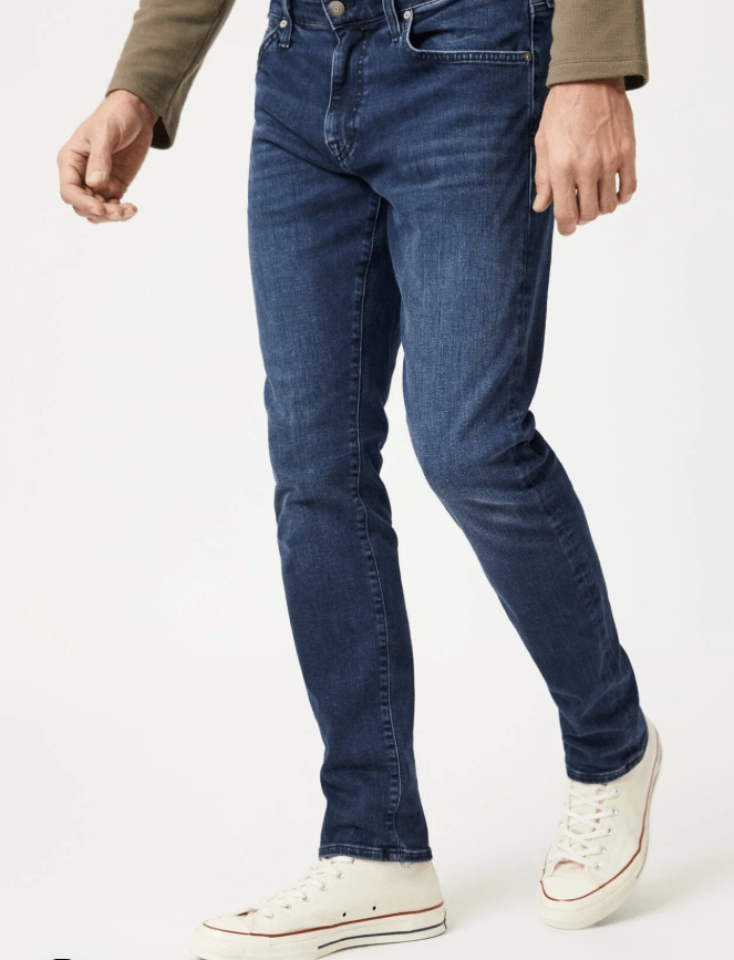 Man wearing blue jeans and white sneakers on a white background