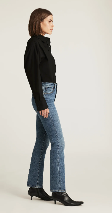 Woman wearing blue jeans and a black top on a white background