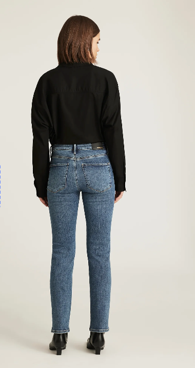 Person wearing blue jeans and a black top on a plain background