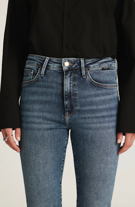 Person wearing blue jeans with a plain background