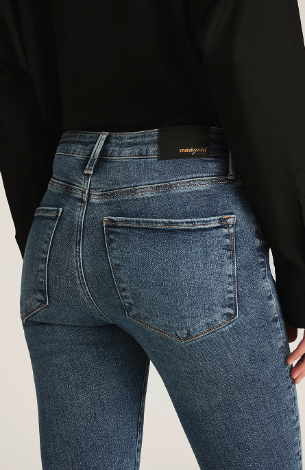Blue jeans with a brand label on the back pocket against a neutral background