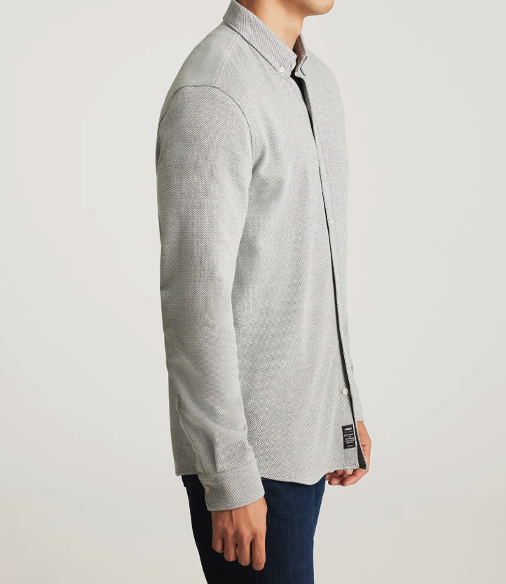 Man wearing a gray button-up shirt on a plain background