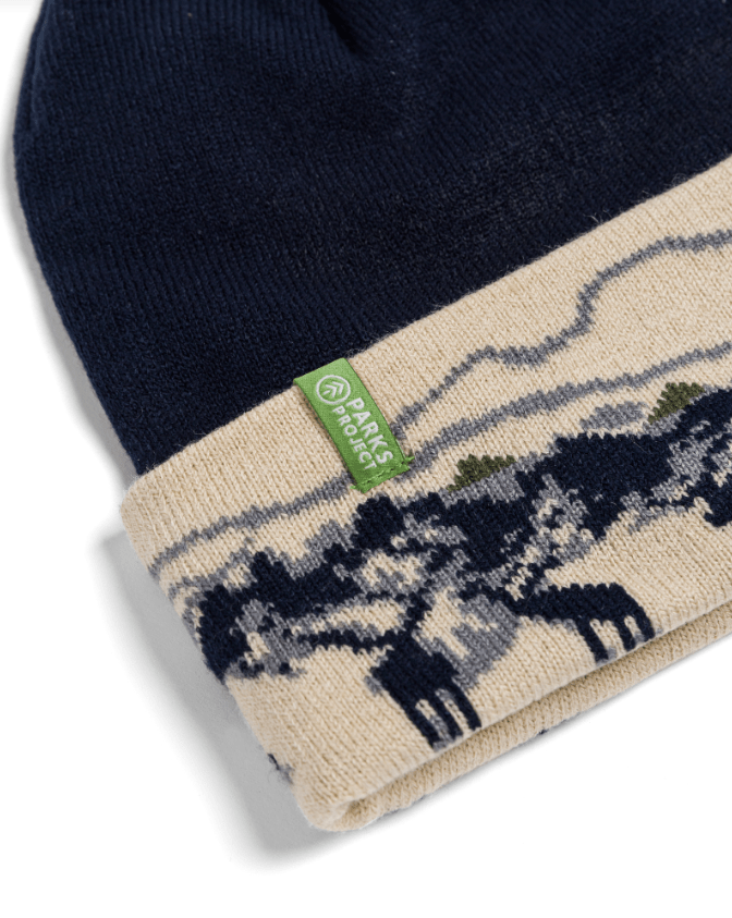 Navy blue beanie with moose pattern and a green label on a white background