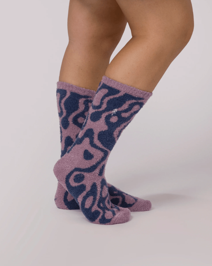Purple patterned socks worn by a person on a white background