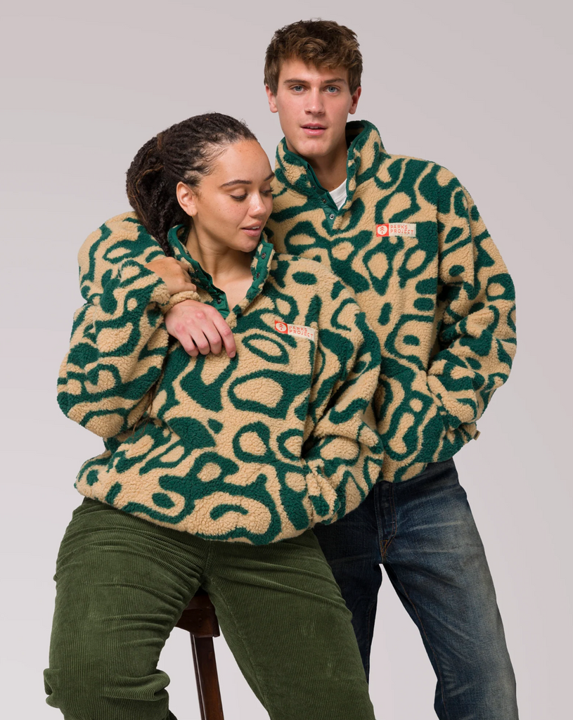 Two people wearing a yellow and green patterned fleece jacket on a plain background