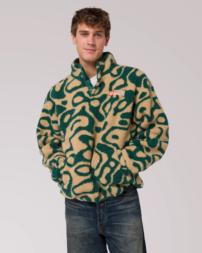 Man wearing a green and beige patterned fleece jacket on a plain background