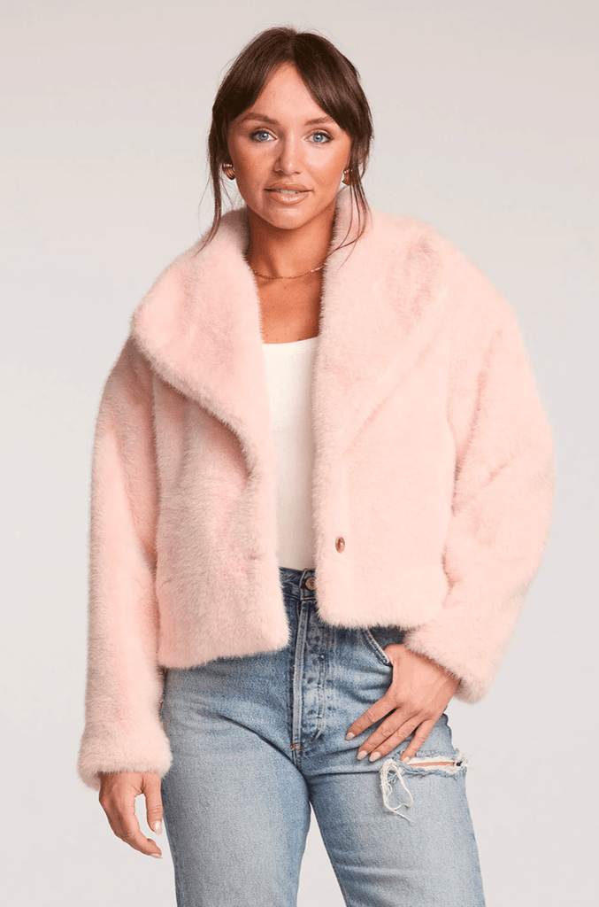 Woman wearing a pink faux fur coat against a white background
