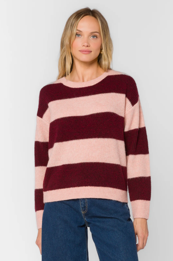 Woman wearing a pink and burgundy striped sweater against a plain background
