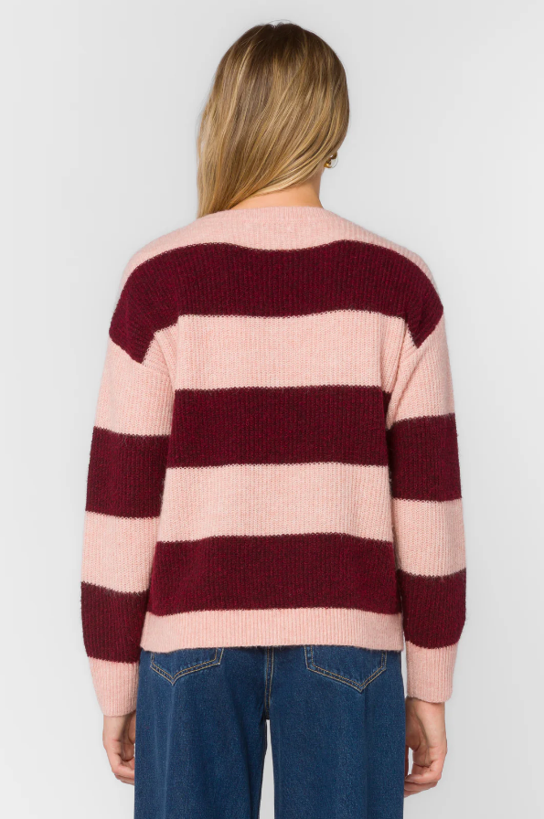 Woman wearing a pink and burgundy striped sweater on a plain background