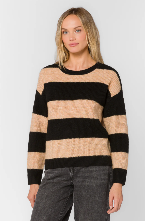Woman wearing a black and beige striped sweater against a white background
