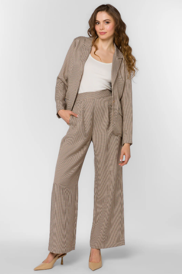 Woman wearing a brown houndstooth suit with a white top on a light gray background