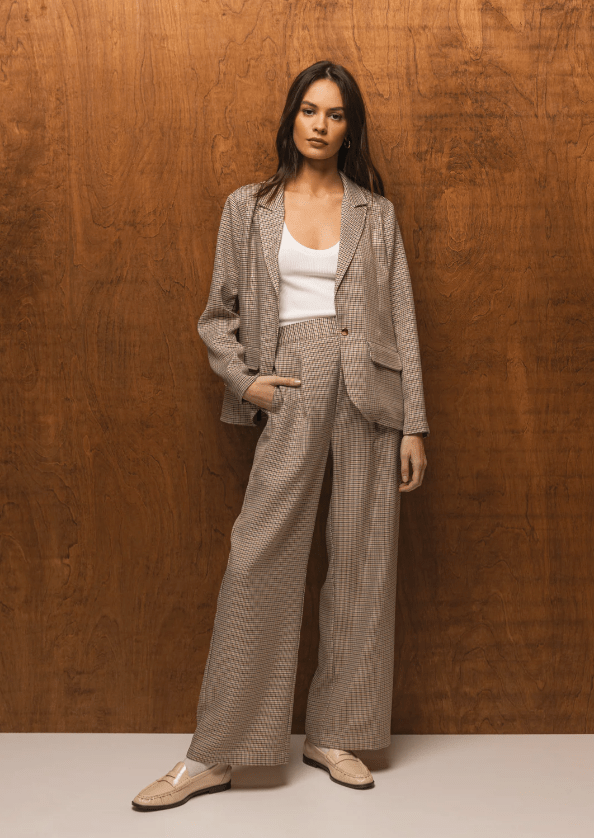 Woman wearing a houndstooth suit against a wooden wall