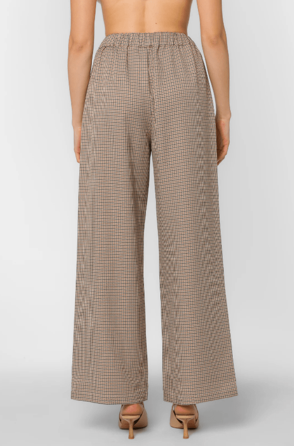 Houndstooth patterned pants worn by a woman on a plain background