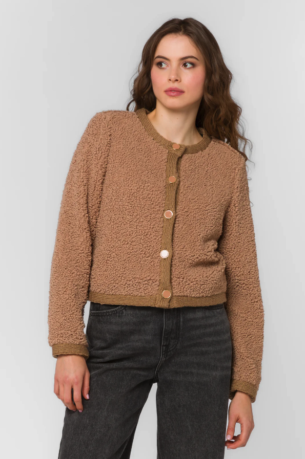 Woman wearing a brown textured jacket with a plain background