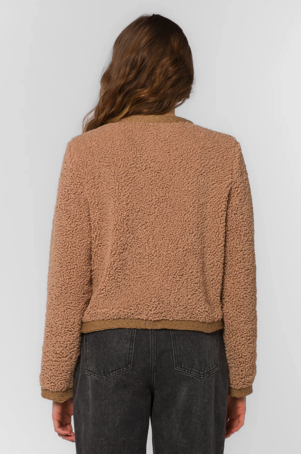 Woman wearing a brown textured jacket against a white background