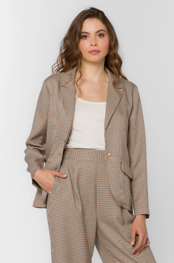 Woman wearing a brown houndstooth suit against a white background