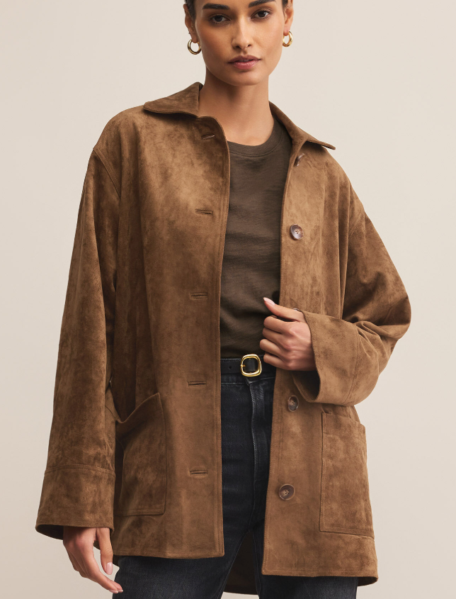 Woman wearing a brown faux suede coat against a plain background
