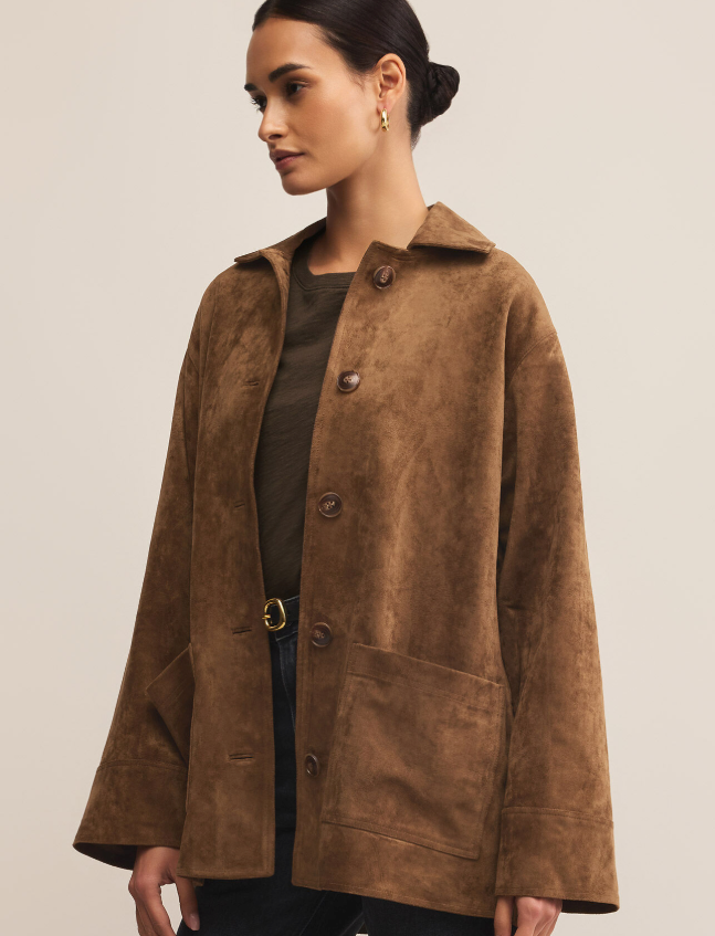 Woman wearing a brown faux suede coat against a plain background
