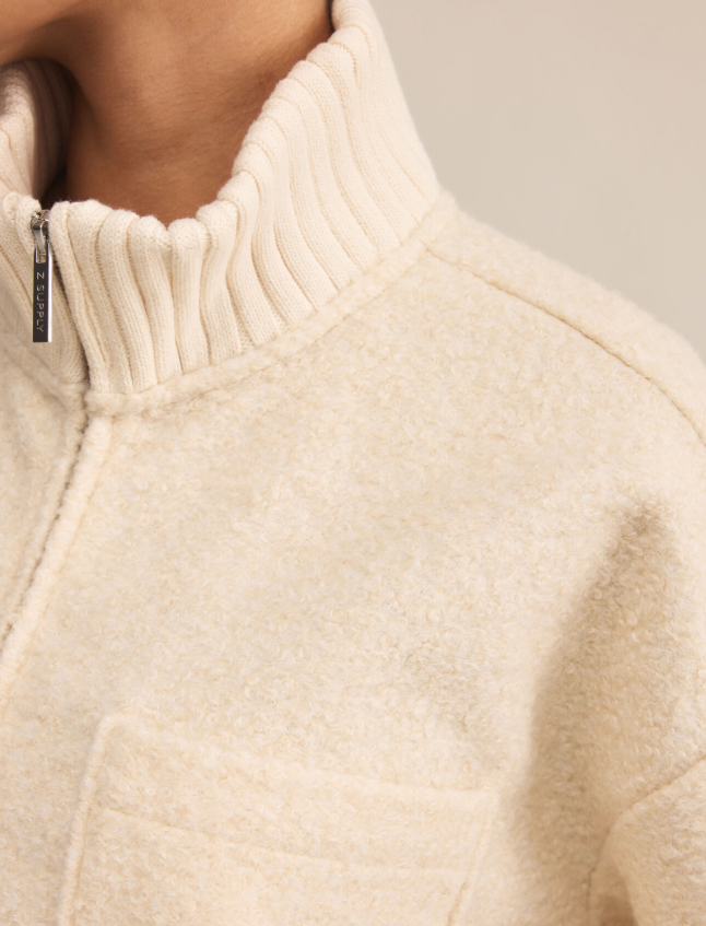 Close-up of a beige fleece zip up jacket on a neutral background
