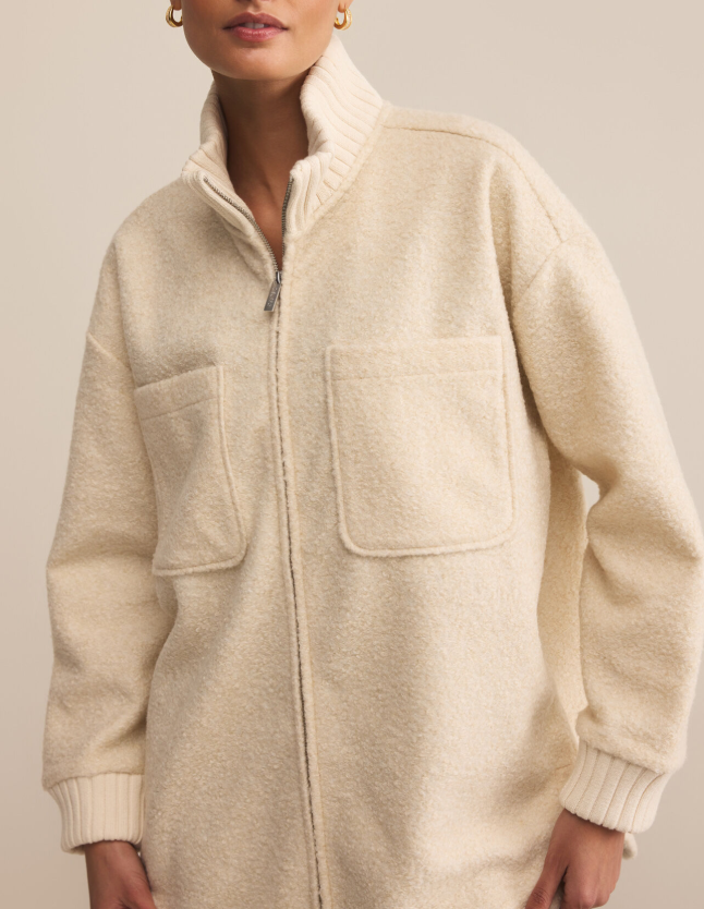 Fuzzy beige fleece zip up jacket worn by a person on a plain background