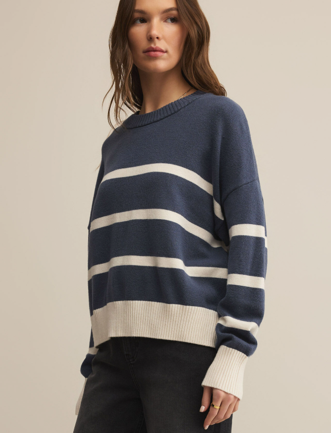 Woman wearing a navy and white striped sweater against a beige background