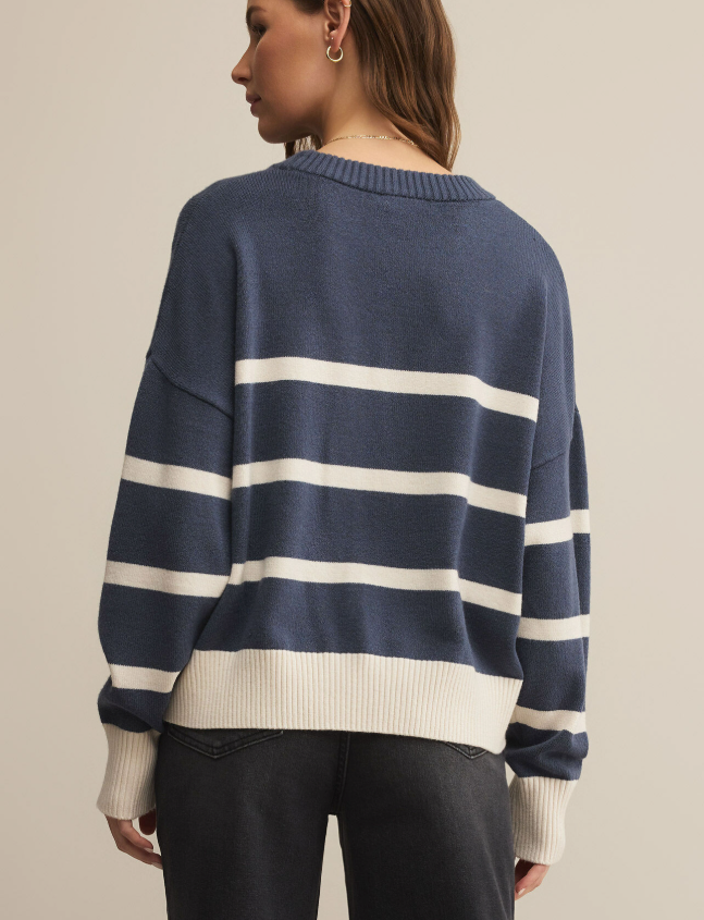 Navy and white striped sweater worn by a person on a beige background