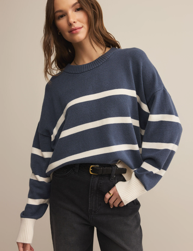 Woman wearing a navy and white striped sweater against a beige background