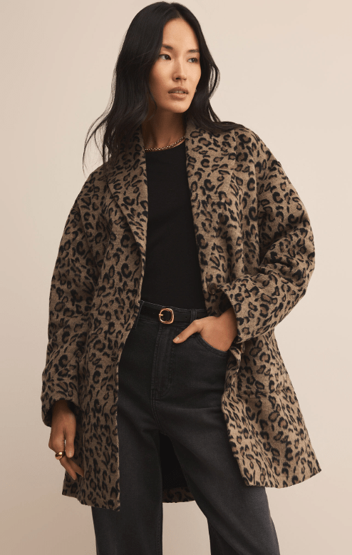 Woman wearing a long leopard print coat, a black shirt, and black jeans.