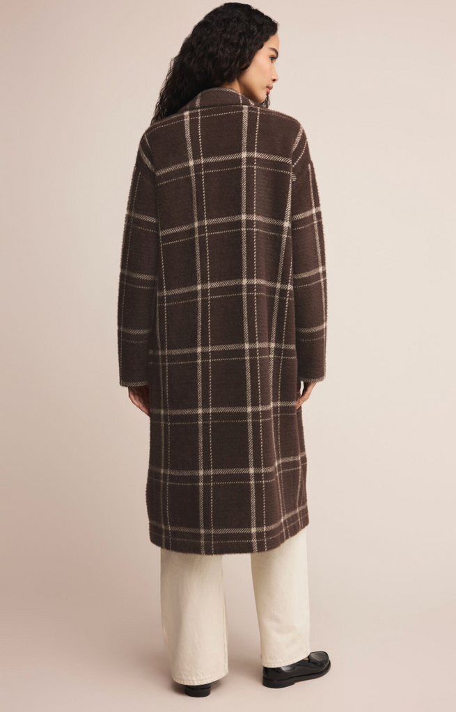 Woman wearing a brown plaid coat against a beige background