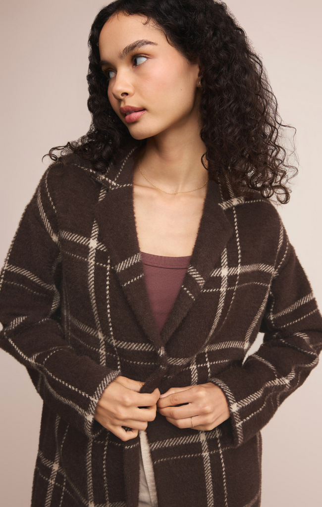 Woman wearing a brown plaid coat against a plain background